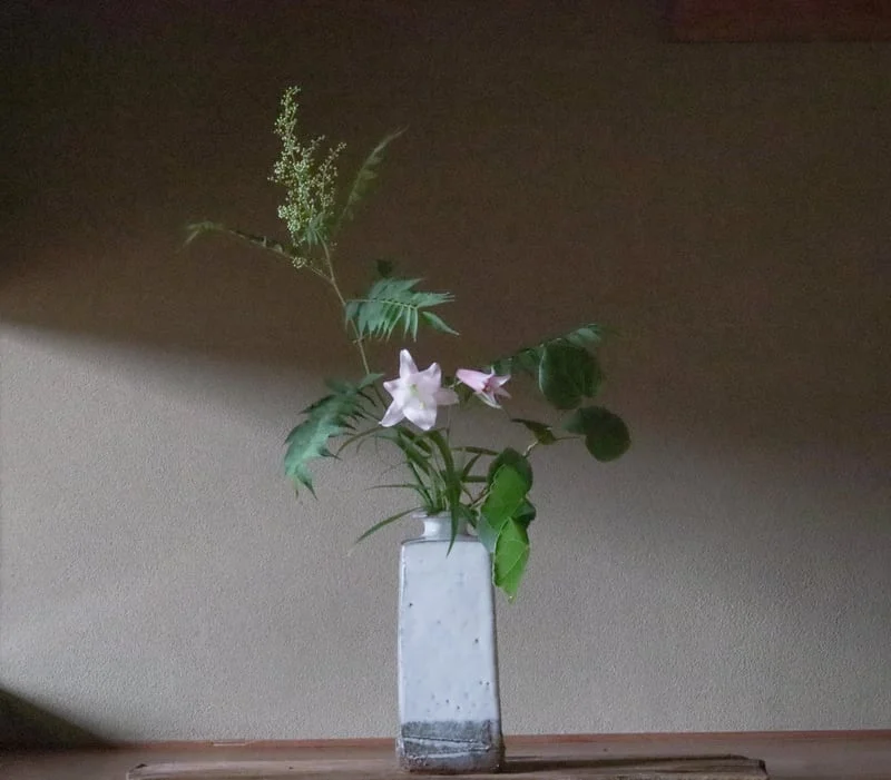 淡い桃色の花と緑の花材を花瓶に生けた例